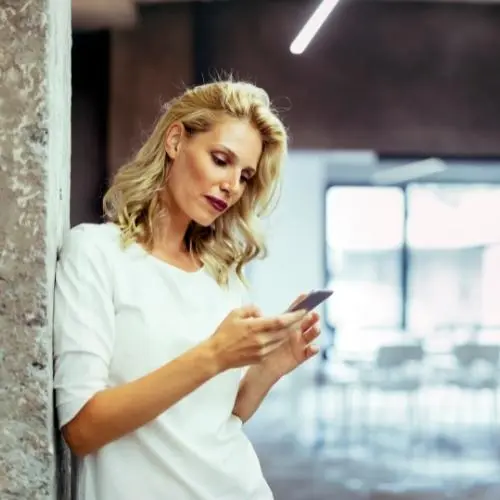 Blonde haired woman on cell phone booking cleaning service